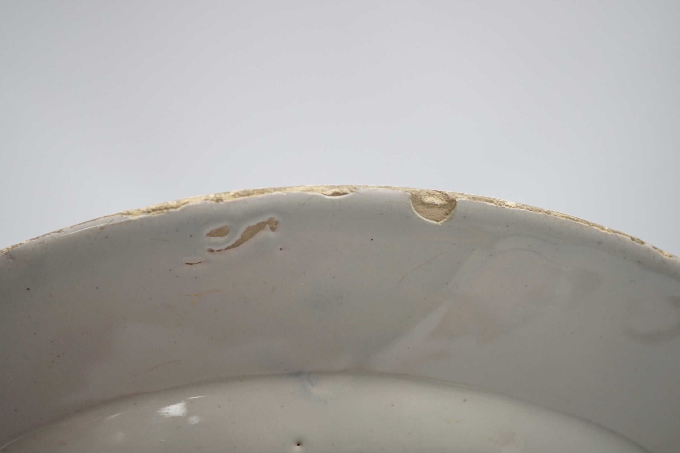 An 18th century Delft dish, decorated with a Chinese scene of a figure with a parasol, diameter 28cm. Condition - damaged to rim